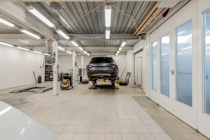 An SUV raised on a lift in a bright, empty auto repair shop