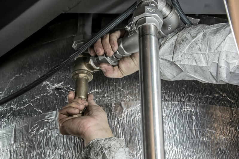 A plumber's hands tightening a brass fitting on a pipe