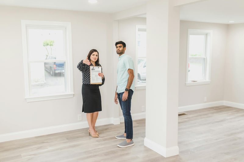 A real estate agent with a clipboard showing an empty home to a buyer