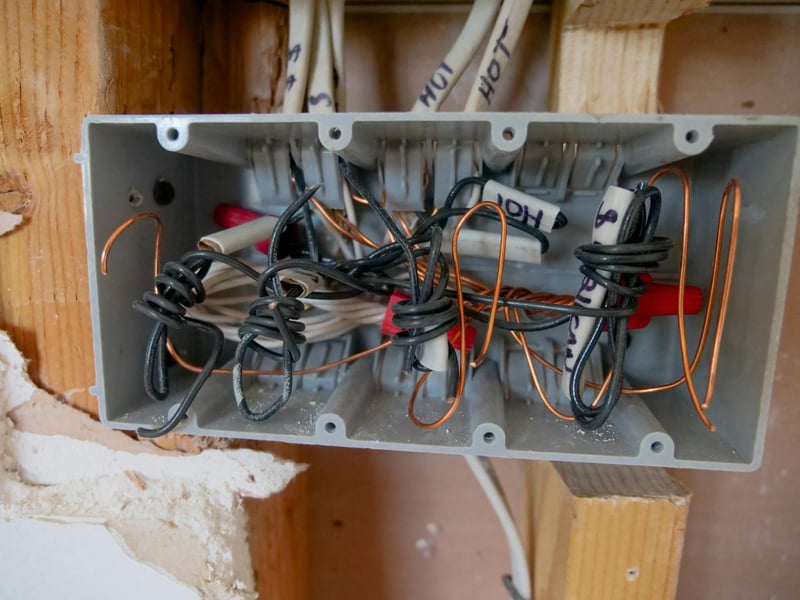 An open electrical box with labelled wires during a rough-in